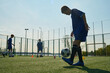 © Mediaphotos - Group of boys practicing soccer skills on outdoor field, one teenager balancing soccer ball on foot while others training in background, wearing sports uniforms