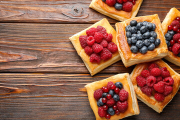 Wall Mural - Tasty puff pastries with berries on wooden table, flat lay. Space for text