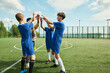 © Mediaphotos - Group of teenage boys and one teenage girl with diverse ethnicities celebrating together on outdoor soccer field, raising hands for high five after successful play during practice