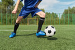 © Mediaphotos - Teenage boy dribbling soccer ball on outdoor field, wearing sports uniform, standing near goal, showing active movement during practice or game, legs and lower body visible