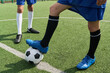 © Mediaphotos - Two teenage boys standing on soccer field, one teenager resting foot on soccer ball while other teenager standing nearby, both wearing sports uniforms and soccer cleats