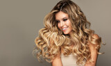 Beauty  blonde girl with long  and   shiny wavy  Hair ,coloring and toning, shatush and balayash .  Beautiful   woman model with curly hairstyle .