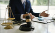 © Natthawadee - Lawyer in suit working at desk with gavel, justice scale, and legal documents, symbolizing law, judgment, and legal decision-making.