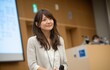 © Road Red Runner - Confident Japanese woman delivers impactful presentation on stage in front of engaged audience during professional seminar