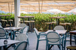 © Raivo - Outdoor terrace with modern tables, chairs, and bar stools under large sunshades. A stylish empty seating area in a sunny resort or beachside café.