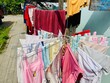 © mrtnd a - Baby clothes on a round iron clothesline or folding hanger, the hot sun is a natural process for drying the laundry