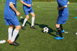 © Mediaphotos - Group of teenage boys playing soccer on outdoor field, focusing on legs and feet in motion around ball, wearing sports uniforms, engaging in active teamwork during practice session