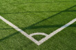 © Mediaphotos - Corner of soccer field showing boundary lines on green artificial turf, capturing precise field markings and texture of synthetic grass, no people visible in scene