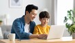 © Kim de Been - Father and son sitting at a desk, looking at a laptop. Two generations using technology together