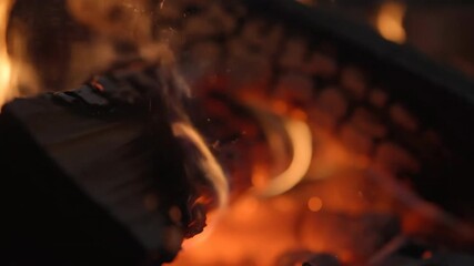 Sticker - a macro shot captures delicate sparks jumping from a slowly burning log, in shallow depth of field b