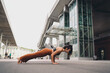 © BullRun - Focused woman performing yoga chaturanga on city street, demonstrating strength and balance. Conceptual wellness image symbolizing empowerment, discipline, mindfulness, and digital lifestyle.