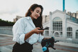 © BullRun - Smiling woman checks smartphone while holding electric scooter, symbolizing digital mobility, eco-friendly technology, and independence in modern professional freelance lifestyle.