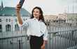 © BullRun - Confident woman in white shirt takes selfie with smartphone outdoors. Conceptual stock image symbolizing empowerment, digital lifestyle, social identity, and modern communication.