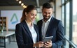 © David - Professional business people, two happy business man and woman executives partners team working together checking corporate results standing in company office using digital tab fintech device..
