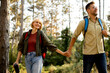© BGStock72 - Couple enjoying a nature hike in the forest during a sunny day, hand in hand with backpacks on