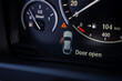 © Aerial Film Studio - Close up view of a BMW X6 instrument cluster showing a fuel gauge, speedometer, and digital display with a door open warning and 104 km range.