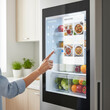 © Ada - Person hand interacting with a large, transparent screen on a smart refrigerator. screen displays the contents inside the fridge with a clean, modern UI,suggests recipes based on available ingredients
