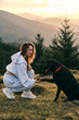 © KatyaPulka - A heartwarming image of a woman bonding with her black Labrador dog in a scenic mountain landscape at sunset.  Loyalty, companionship, and outdoor adventures are beautifully captured.