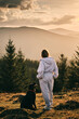 © KatyaPulka - A woman and her dog enjoy the breathtaking view of misty mountains at sunset. The serene landscape is complemented by the bond between the owner and her loyal companion.