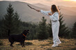 © KatyaPulka - A young woman enjoys playing fetch with her dog in a beautiful mountain setting at sunset. Perfect for illustrating outdoor activities, pet ownership, or a healthy lifestyle.