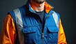 © Raisa - Close-up of reflective safety vest on construction worker. Blue, orange uniform with reflective strips, zipper, pockets. Protective gear for industrial, professional workwear, high visibility apparel.