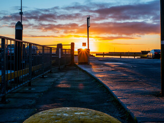 Wall Mural - A sun rise over a marina with silhouettes of masts of many boats and yachts docked. Teal and orange color scheme. Calm and relaxing mood. Port of Galway, Ireland.