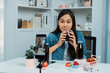 © InfiniteFlow - Smiling young beautiful Asian reviewing tasty mixed strawberry and cherry juice detox drinks, showing healthy product to promote for special promotion selling on social media online record. Stratagem.