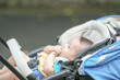 © Masakazu Tokashiki - A baby is sitting in a stroller and is holding onto a towel. The stroller is blue and white
