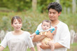 © Masakazu Tokashiki - A man is holding a baby while a woman looks on. The baby is wearing a blue shirt