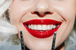 © VICHIZH - Bright smile of a woman with red lipstick holding makeup brushes, highlighting beauty and confidence.