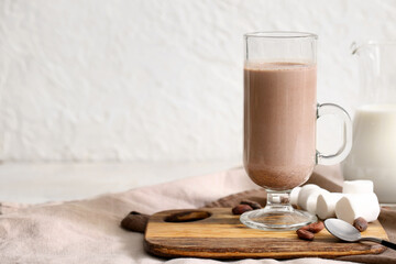 Wall Mural - Glass cup of sweet chocolate milk with marshmallows and cocoa beans on white background