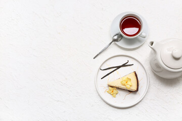 Wall Mural - Plate with piece of sweet vanilla cheesecake and cup of tea on white background