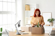 © Pixel-Shot - Young happy redhead businesswoman with cardboard box of belongings in office on moving day