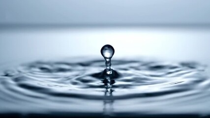 Wall Mural - ﻿A single water droplet impacts a still liquid surface, creating a beautiful slow motion splash with elegant ripples and soft light water, background, wave