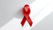 © Unplanned_Pixel - Close-up of a red ribbon symbol on a white background, clean and minimalist style.