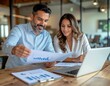 © Oleksandra Litvinova - Two Colleagues Discussing Business Strategy with Laptop and Documents in Modern Office