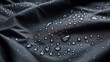 © Amin Rajput - Close up of water droplets on dark fabric showing waterproof material texture