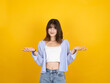 © Designerant - Woman spreading hands aside, portrait of young caucasian 20s trendy cute woman spreading hands aside smiling looking camera isolated on yellow studio background. Wear white top and shirt. Copy space.