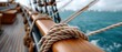 © ZinaZaval - Close-up of a rope knot on a wooden railing, with vibrant blue ocean waves and clear sky creating a tranquil maritime atmosphere