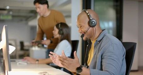 Diverse coworkers celebrating client praise on headset in open-plan office with tablet, copy space