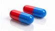 © Nidae - Two pharmaceutical capsules on a white background—one solid red, the other blue with a transparent half revealing small white granules inside—highlighting contrast in formulation and controlled dosage