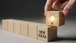 © TamimTech - Hand places a glowing lightbulb block on 'new ideas' creating innovation and inspiration for business strategy and problem solving