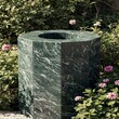 © Waheed - Outdoor garden fountain base designed with green marble tiles surrounded by flowers and lighting creating harmonious natural elegant environment