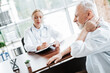 © deagreez - Elderly man consulting a doctor for neck pain during a routine medical appointment in a modern clinical setting