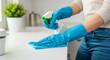 © NikProArt - Hands in blue gloves spray cleaning solution onto kitchen counter then wipe with microfiber cloth for spotless shine and hygiene