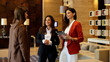 © PeopleVideos - Businesswomen meeting in a modern hotel lobby, discussing corporate strategy and partnership using a digital tablet
