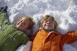 © YanabY - Kids enjoying a winter day making snow angels in bright snow under clear blue sky