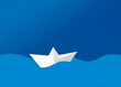 © Westend61 - Paper boat floating on blue ocean waves illustration