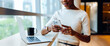 © (JLco) Julia Amaral - Woman texting on a smartphone while standing near a laptop in an office