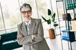 © deagreez - Confident businesswoman posing in a modern office wearing formal attire symbolizing success and professionalism.